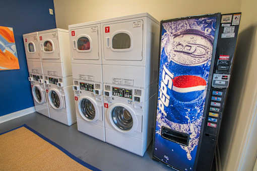 A row of washing machines in front of a vending machine.