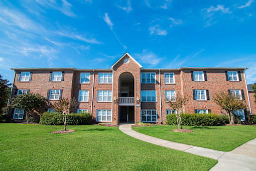 A large brick building with a green lawn in front.