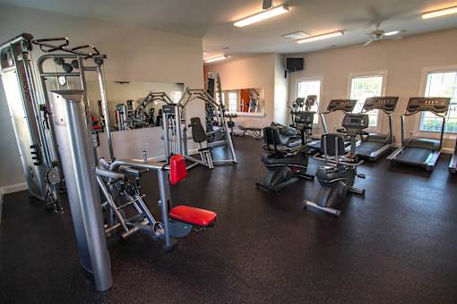A gym with a variety of equipment including treadmills, weights, and exercise machines.
