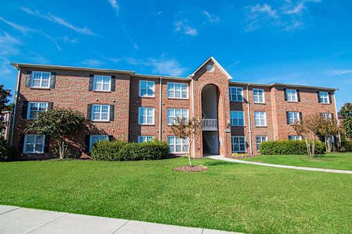 A large red brick building with a green lawn in front.