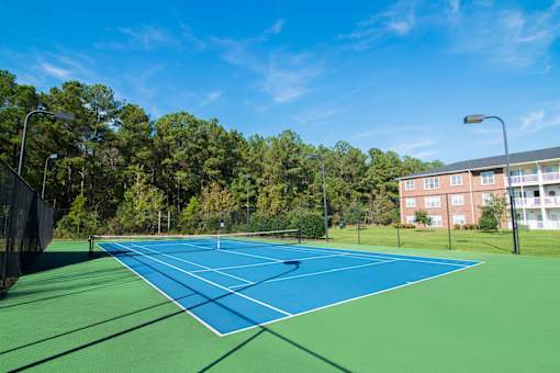 A tennis court surrounded by trees and a building.