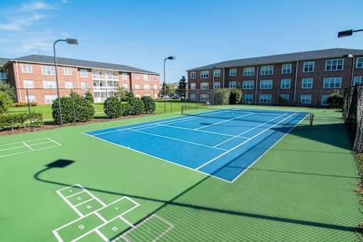 A tennis court is surrounded by apartment buildings.