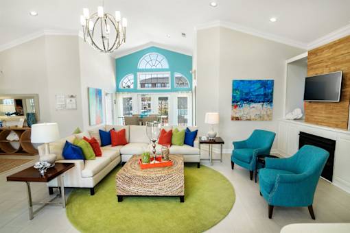 A living room with a white couch, a green rug, and a fireplace.