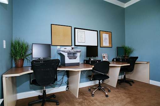 A room with a blue wall and a desk with a computer and printer on it.