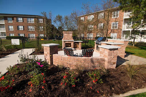A brick fireplace with a black and white chair sits in a garden.