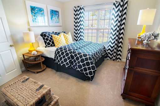 A bedroom with a black and white bedspread and a window with black and white curtains.
