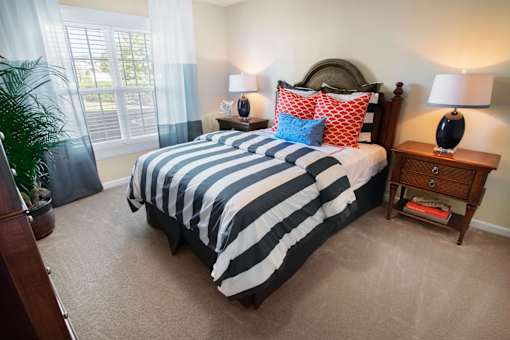 A bedroom with a large bed and two lamps.