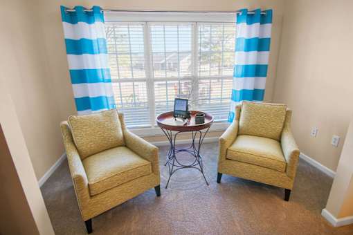 Two chairs and a table in a room with a window.