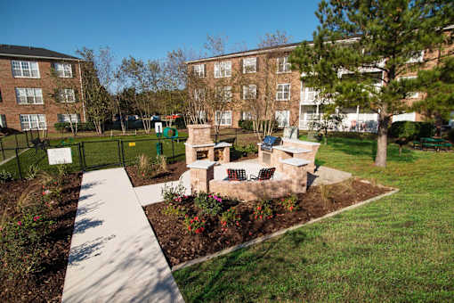 A small garden area with a bench and a fence in front of a building.