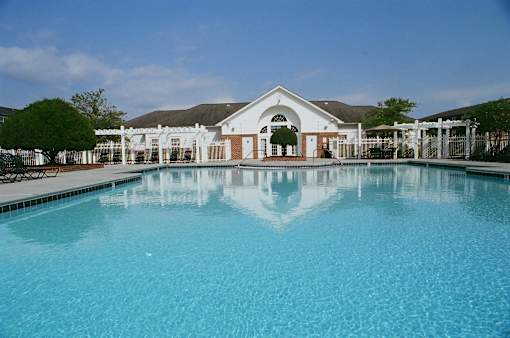 A large swimming pool in front of a building with a white facade.