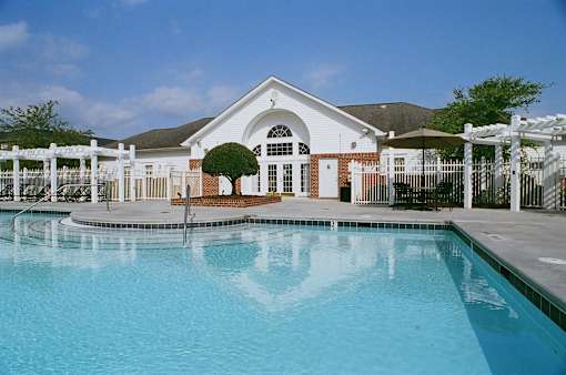 A white building with a pool in front.
