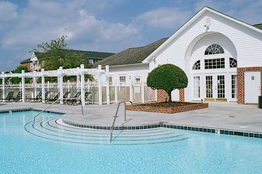 A white house with a pool in front.