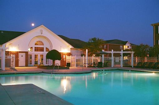 A building with a pool in front of it at night.
