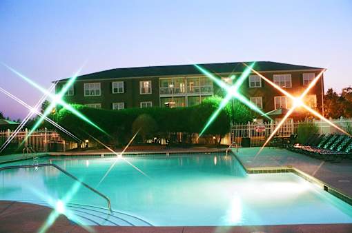 A pool in front of a building with lights crossing over it.