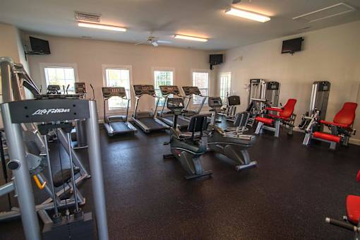 A gym with a variety of equipment including treadmills, weights, and exercise machines.