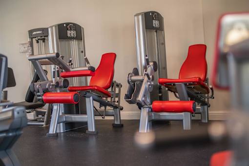 A gym with red chairs and silver machines.