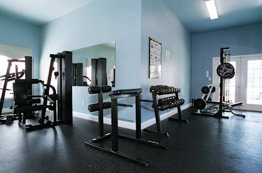 A gym with a variety of equipment including a weight bench, a leg press machine, and a cable machine.