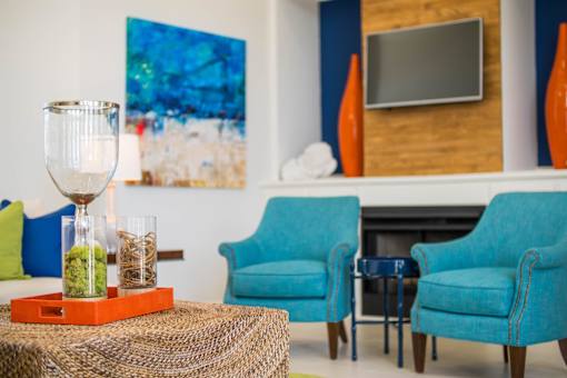 A living room with blue chairs and a painting on the wall.