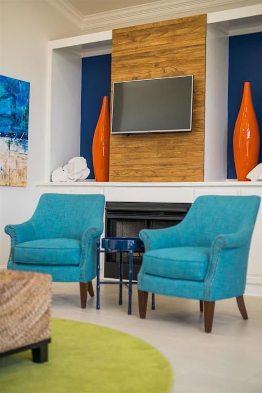 Two blue chairs are in front of a fireplace.