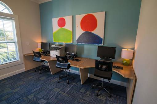 A room with a blue carpet and a desk with a computer and a chair.
