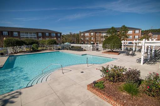 A swimming pool surrounded by a concrete patio and a brick wall.