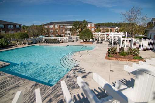 A pool surrounded by white railings and a white pergola.