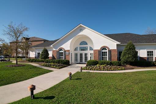 A white building with a red brick border and a green lawn in front.