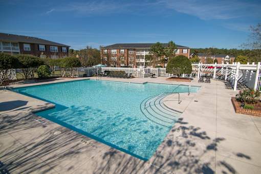 A large outdoor swimming pool with a white fence around it.