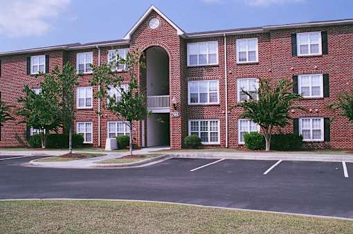 A red brick building with a parking lot in front.