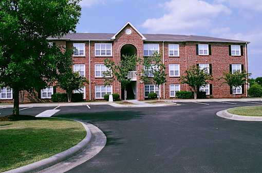 A large red brick building with a curved driveway in front.