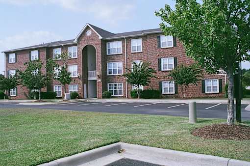 A brick apartment building with a tree in front.
