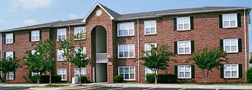 A red brick apartment building with a tree in front.