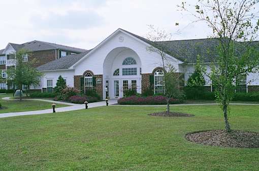 A white building with a green lawn in front.