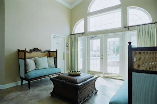 A large bedroom with a canopy bed and a footstool.