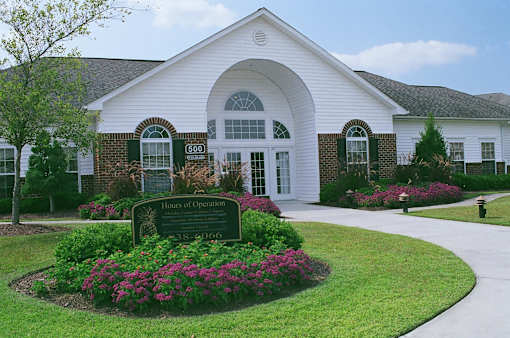 A white building with a sign in front that says Hours of Operation.