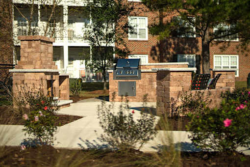 A brick building with a black door and windows is surrounded by a garden.