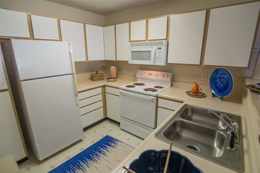 A kitchen with white appliances and a blue mat on the floor.