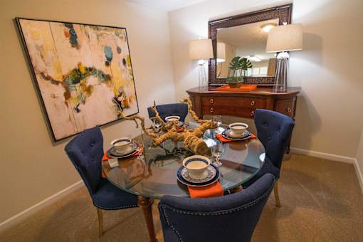 A dining room with a glass table and blue chairs.