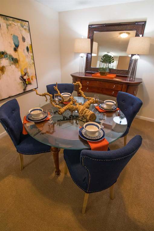 A dining table with four chairs and a mirror above it.