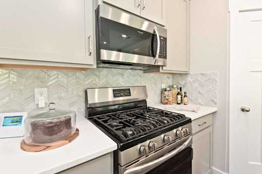 A kitchen with a stove, microwave, and oven.