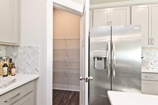 A kitchen with a refrigerator and a counter with condiments.