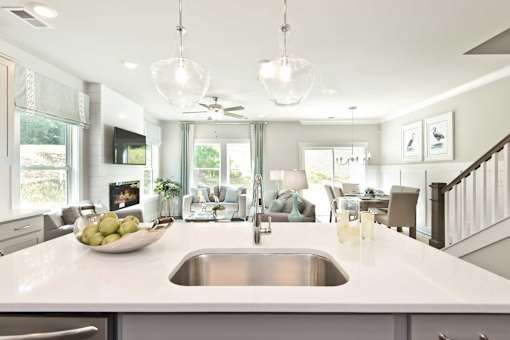 A kitchen with a white counter top and a stainless steel sink.