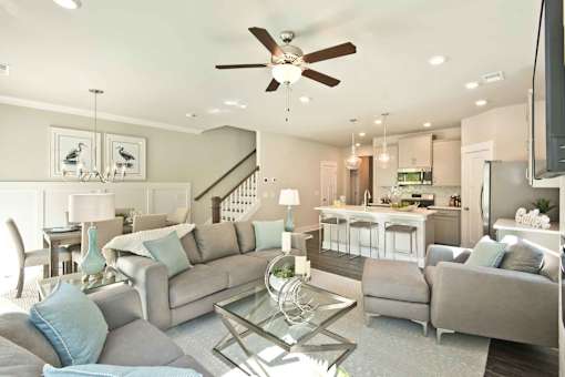 A living room with a grey couch and a glass coffee table.