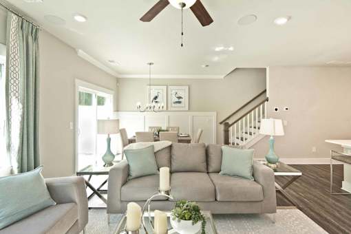 A living room with a grey couch and a glass coffee table.