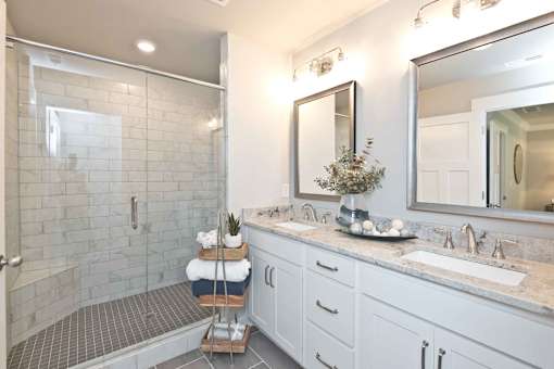 A bathroom with a walk-in shower, double sinks, and a large mirror.