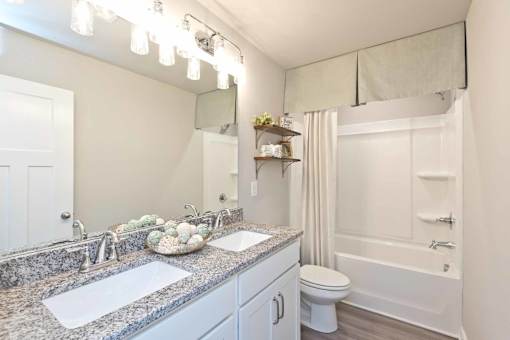 A bathroom with a granite countertop and a white toilet.