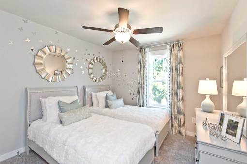 A bedroom with a white bed and a ceiling fan.