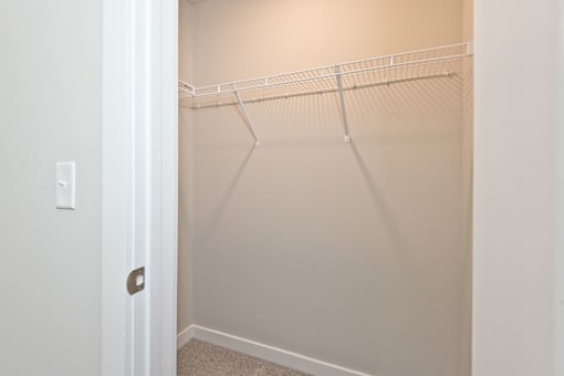 Empty white closet with a white door and a white light switch.