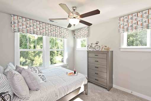 A bedroom with a bed, dresser, and a ceiling fan.