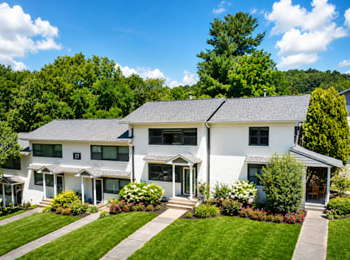 A white house with a grey roof and a green lawn in front.